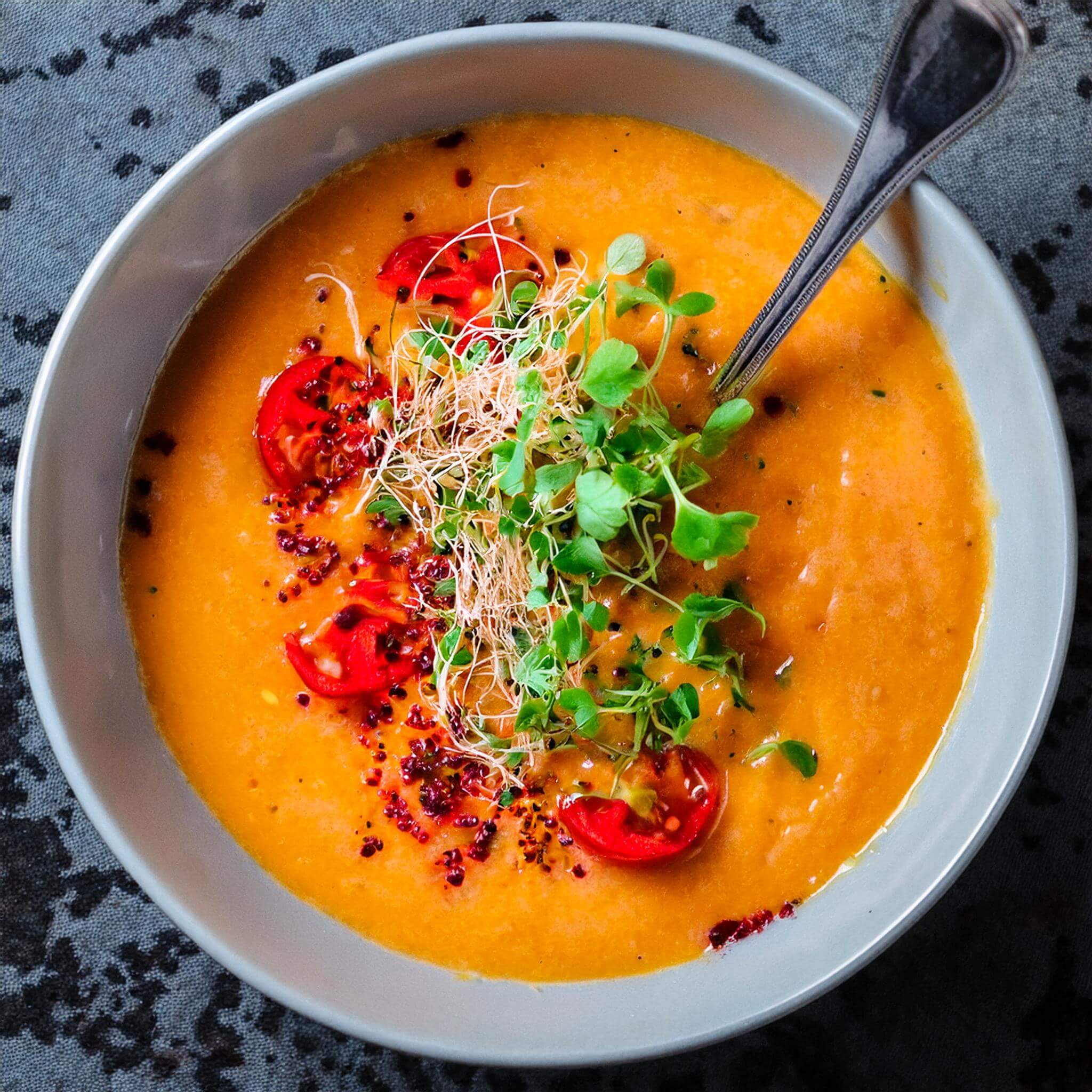 Creamy red lentil soup topped with microgreens and tomatoes.