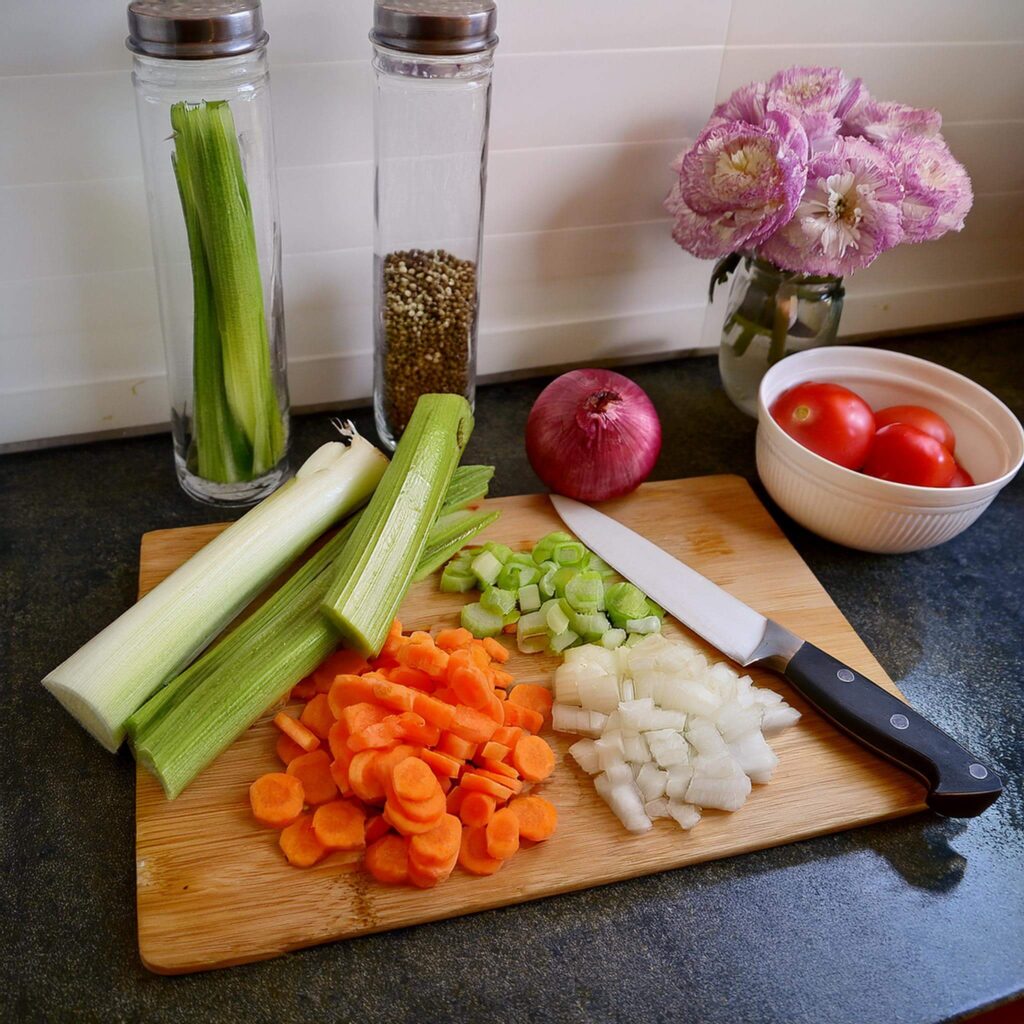 Chopped vegetables on a wooden board with a knife.