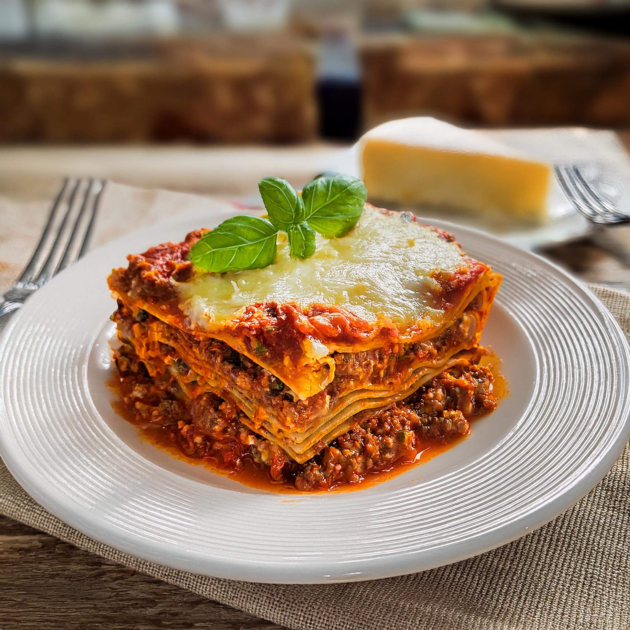 Slice of lasagna topped with melted cheese and basil.